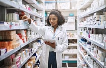 A pharmacist assisting a customer in a well-organized pharmacy store filled with various medications and health products.