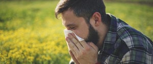 a man wipes his nose with a handkerchief because of an allergy