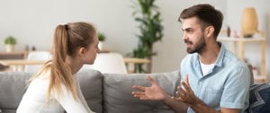 A couple engaged in a serious conversation on a couch, having a heartfelt discussion about navigating toxic relationships and depression.