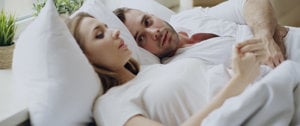  A man and woman lying in bed together, sharing a moment of comfort and support amidst discussions of anxiety.