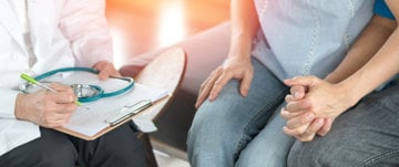 A doctor is seen holding hands with two people, illustrating emotional support during the egg freezing experience after cancer.