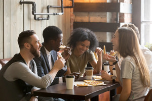 A group of friends enjoying pizza together at a restaurant, fostering connection and joy amidst depressed.