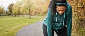 A woman performs a stretching exercise on a path, symbolizing determination amidst asthma struggles.