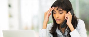 a woman at work is talking to a client on the phone while she has a headache