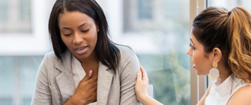 Two women engaged in conversation in an office setting, discussing heart disease misconceptions and awareness.