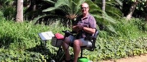 A man seated on a green scooter, symbolizing accessible travel options for those with MS during holidays.