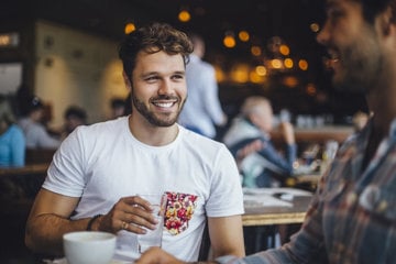  A man smiling at a restaurant table, embodying joy and self-love amidst his journey with depression.