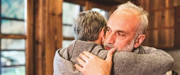 An older man hugs another man, representing emotional support and connection in times of depression crisis.