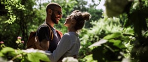 A couple embraces in a peaceful woodland, illustrating the importance of emotional support in discussing health challenges.