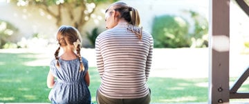 A woman and a little girl sit on a porch, engaged in a conversation about asthma awareness and health education.