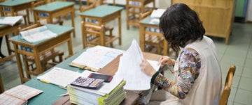 A woman working at a desk in a deserted classroom