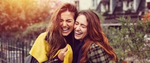 Two women enjoying a moment of laughter in the city, emphasizing the relationship between emotions and asthma symptoms.