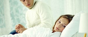 a man sits next to a hospital bed and holds his sick wife's hand, supporting her