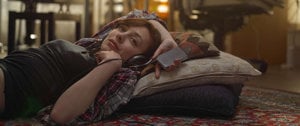 A woman lies on a rug with headphones, reflecting on the mental health effects of lockdown during her quiet moment.