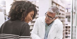 A couple reviews a prescription in a pharmacy, emphasizing the importance of caregiver-friendly services in medication management.