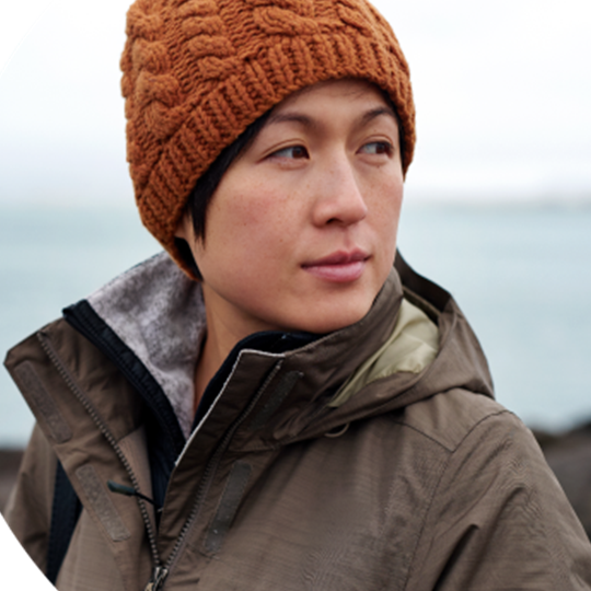 A woman in a brown knitted hat, symbolizing warmth and support in the context of cancer awareness.