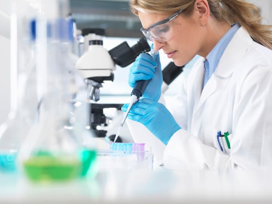 A woman in a lab coat examines a test tube, showcasing her focus and dedication to scientific research.