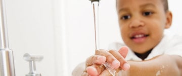 A young boy is engaged in washing his hands with soap, promoting fun and education in proper handwashing practices.