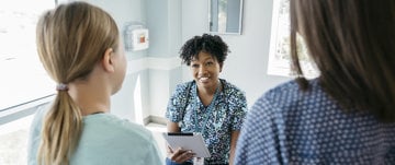  A woman converses with another in a hospital room, highlighting Teva Canada's commitment to healthcare solutions.