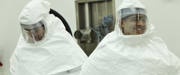 Two men in protective clothing and masks, engaged in innovative specialty product development.