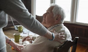 A woman gently holds the hand of an elderly man, symbolizing care and connection between generations.