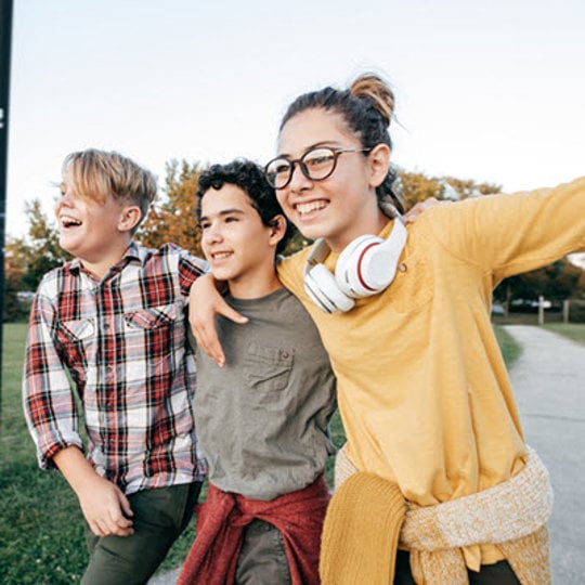 A cheerful group of three young people smiles and poses for the camera, capturing a joyful moment of camaraderie.