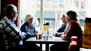 Three older individuals seated at a restaurant table, engaged in conversation and enjoying their meal together.