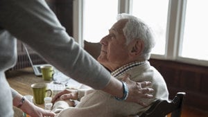 A person gently holds the hand of an elderly man, symbolizing care and connection between generations.