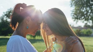 In the sunlight, two women share a meaningful glance, their expressions reflecting warmth and mutual understanding.