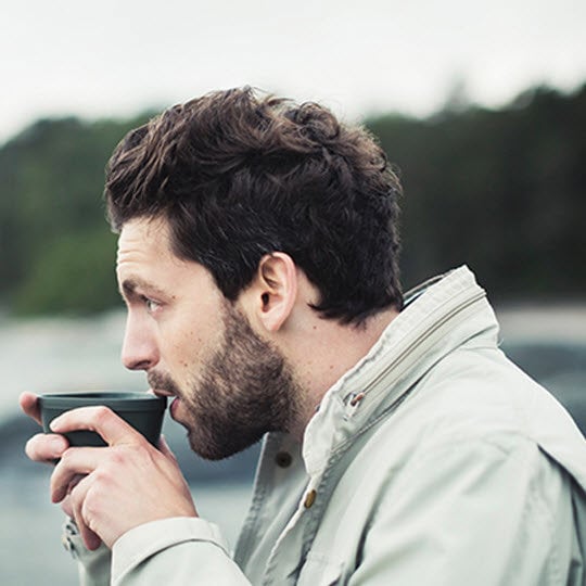 A man drinking from a cup at the beach