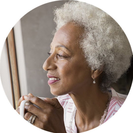 An older woman with white hair enjoys a cup of coffee, reflecting on the safety and efficacy of generic medications.