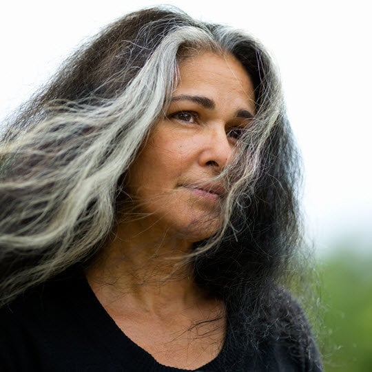 A woman with long hair dressed in a black shirt, exuding a sense of poise and elegance.